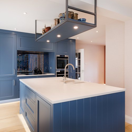 Blue shaker-style kitchen with a hanging shelf above the island and built-in ovens