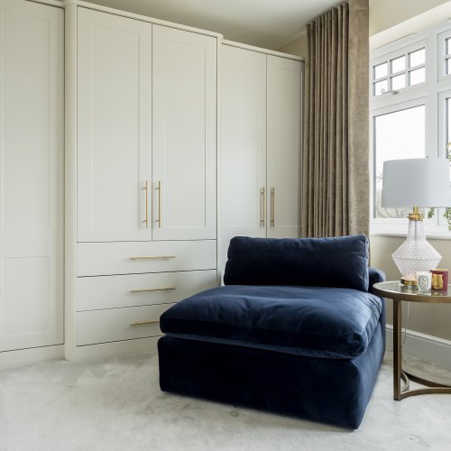 Cream fitted wardrobes with central drawers in a bedroom with a bay window