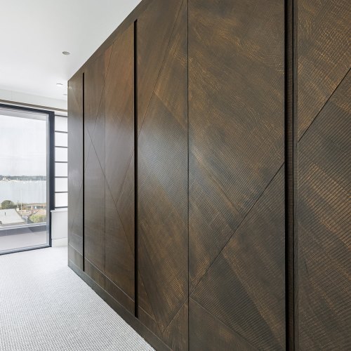 Floor-to-ceiling walnut wardrobe doors with diagonal grain panels