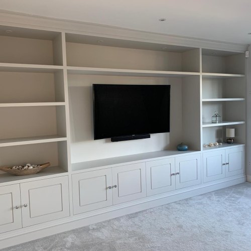 Off-white built-in media wall with a wall-mounted TV, open shelves and cupboards below