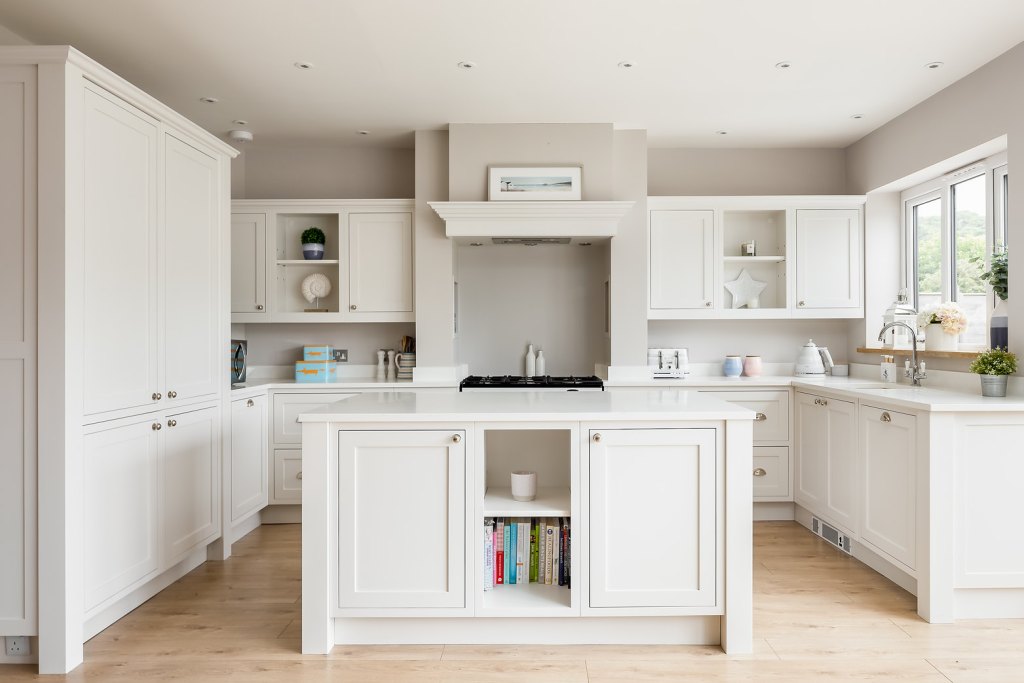 Off-white shaker-style kitchen with a central island, open shelves and a range cooker